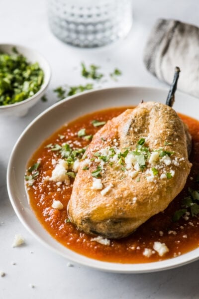 Chile relleno on a plate with red salsa.