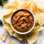 Roasted tomato salsa in a bowl surrounded by tortilla chips.