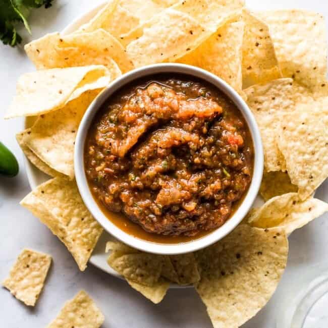 Asado salsa de tomate en un recipiente rodeado de chips de tortilla.