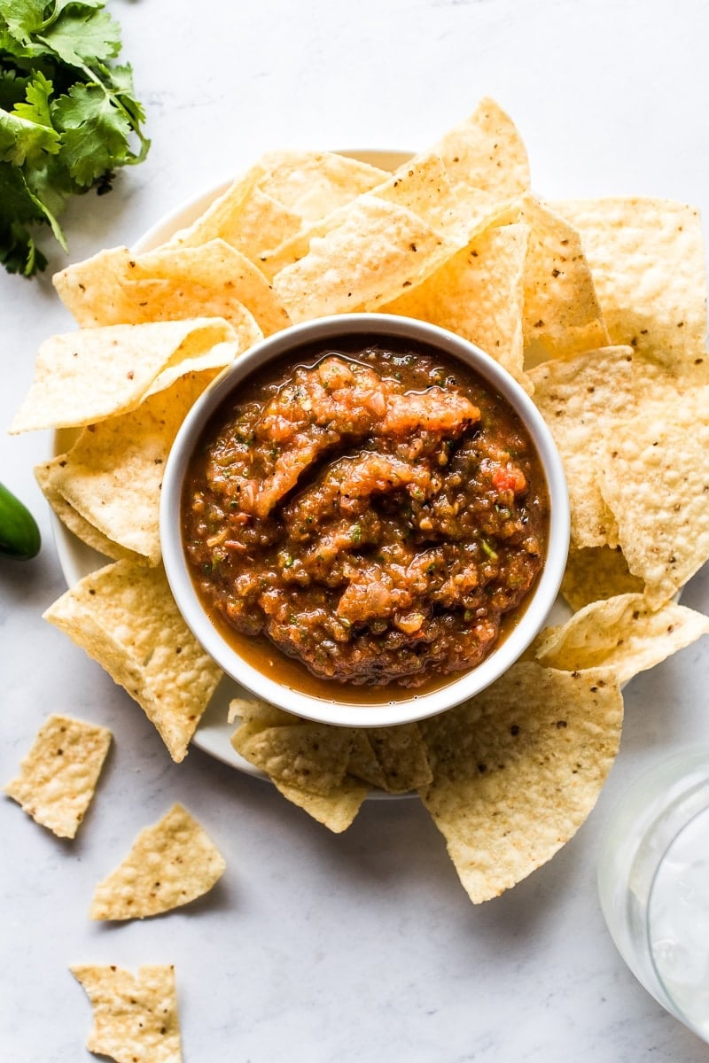 Roasted tomato salsa in a bowl surrounded by tortilla chips.