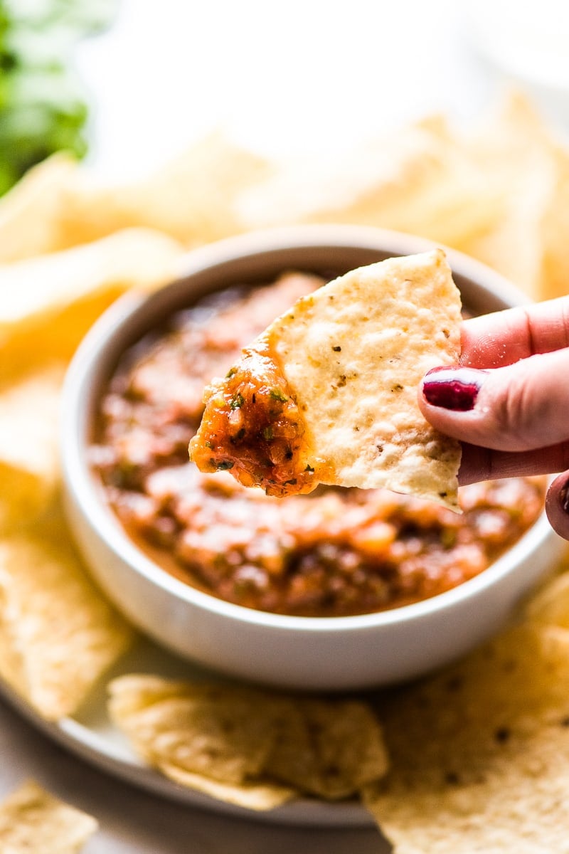 Ein Tortillachip mit gerösteter Tomatensalsa darüber.