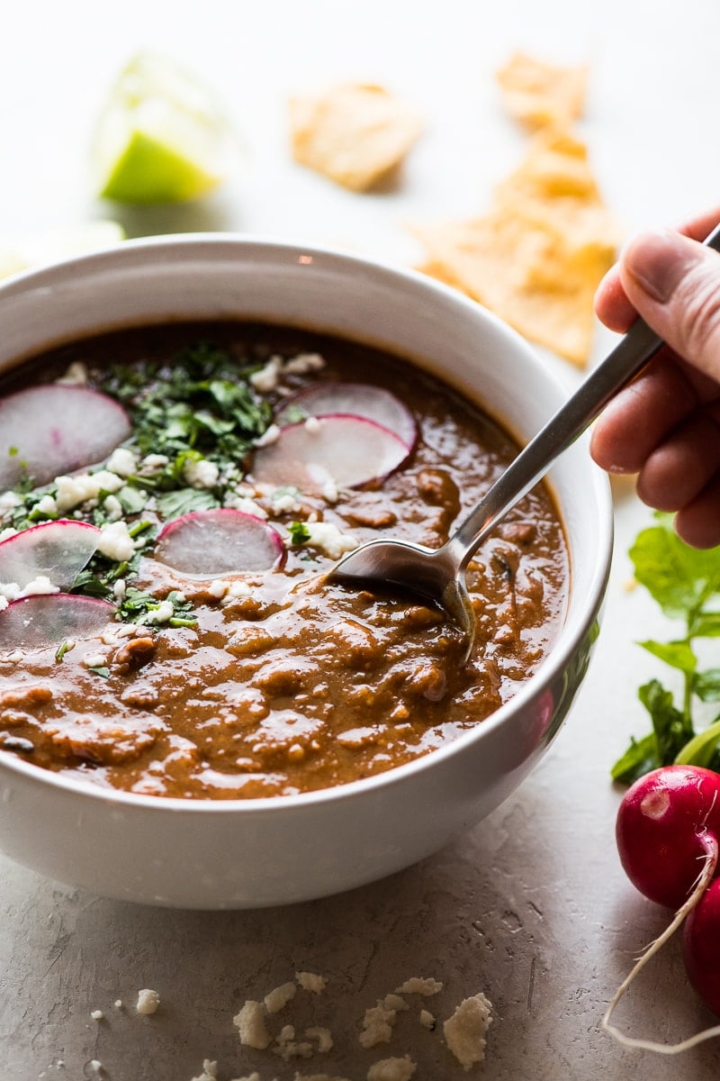 A hand grabbing a spoonful of pinto bean soup