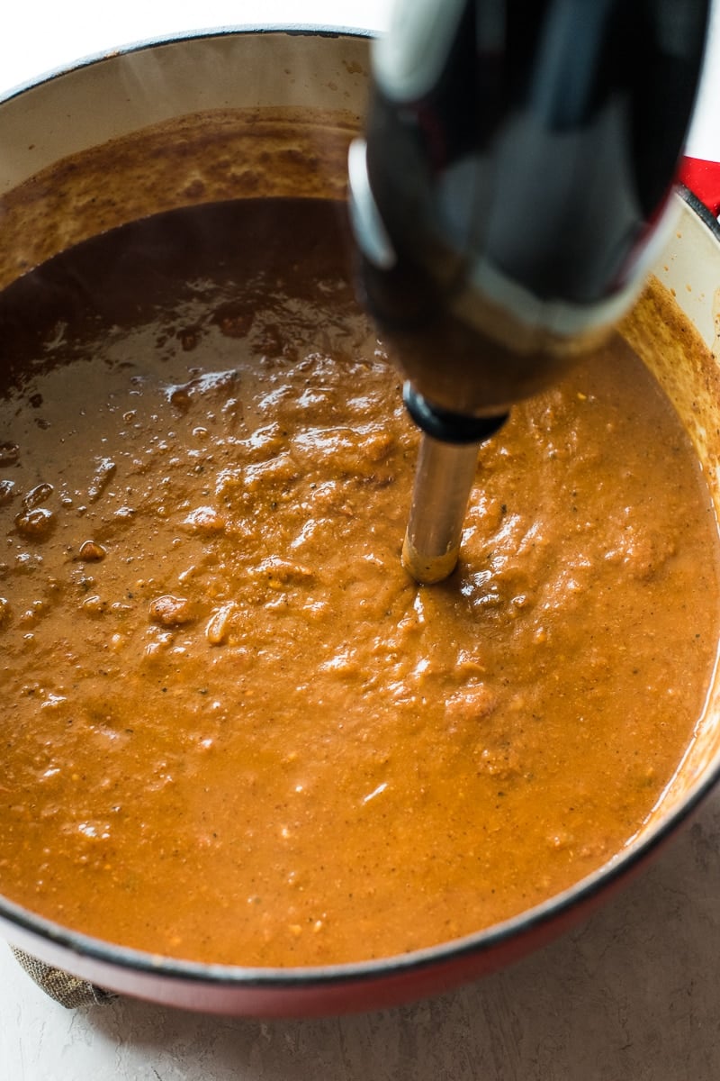 An immersion blender in a pot of pinto bean soup