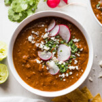 Pinto bean soup garnished with cilantro a cotija cheese.