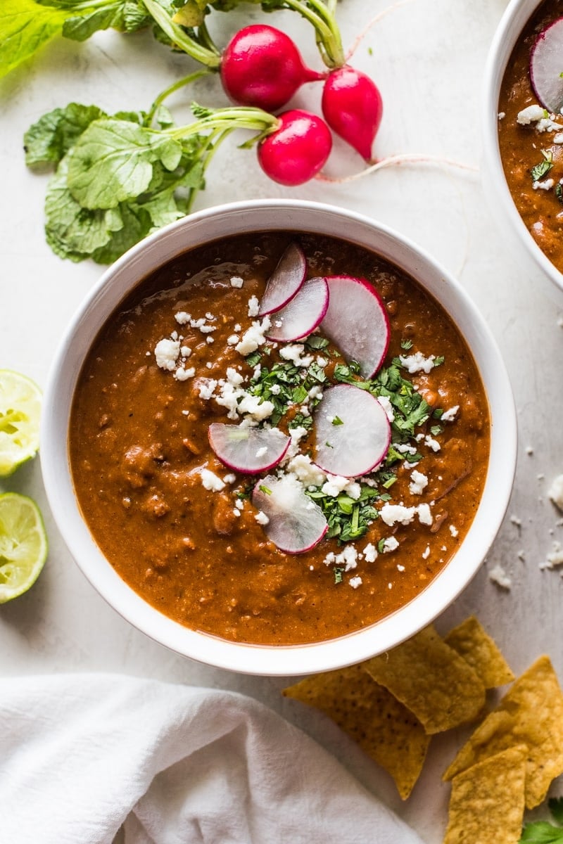 Pinto bean soup garnished with cilantro a cotija cheese.