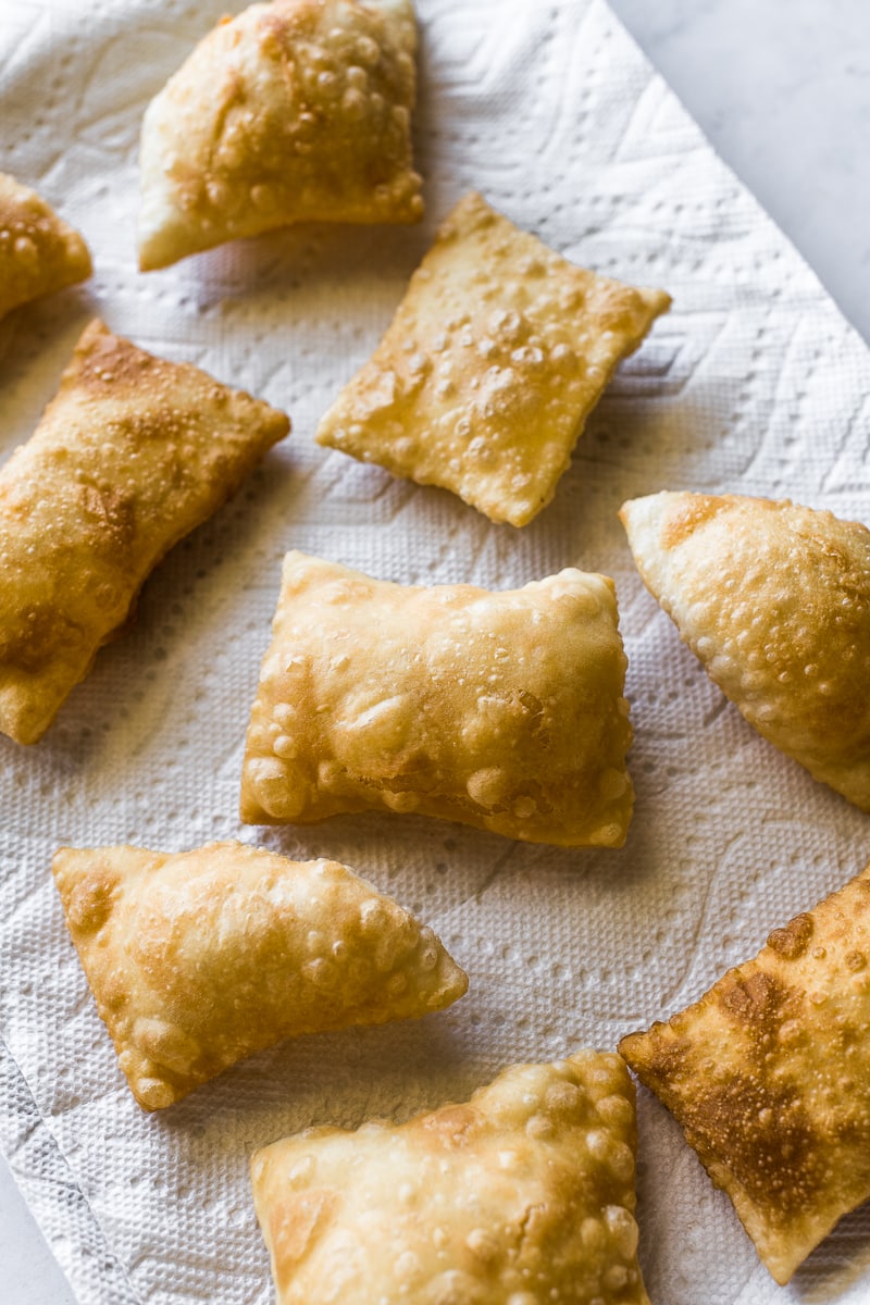 Fried sopapillas draining on a paper towel.