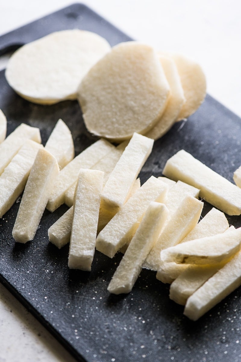 Sliced raw jicama on a cutting board.