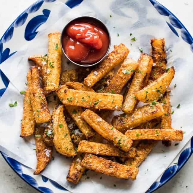 Baked jicama fries on a blue plate with a side of ketchup.