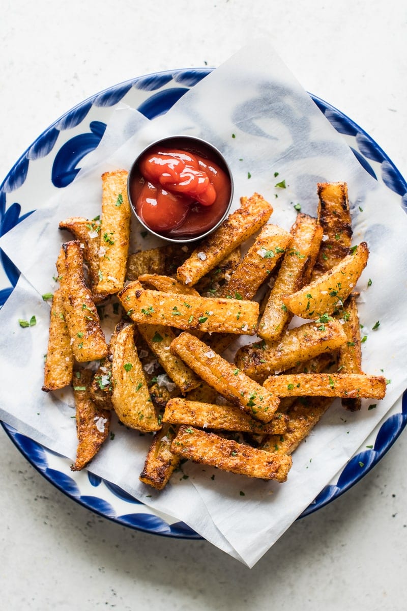 Baked jicama fries on a blue plate with a side of ketchup.