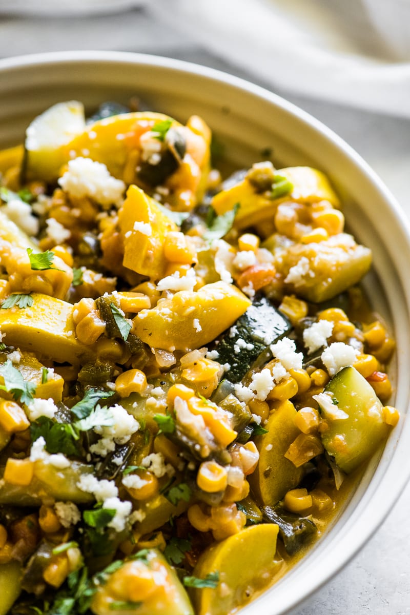 Calabacitas in a bowl topped with cilantro and cotija cheese.