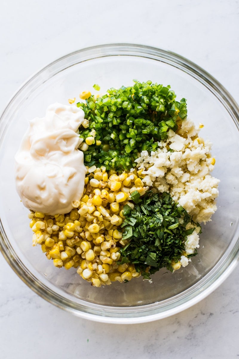 Corn, mayonnaise, cilantro, jalapenos and cotija cheese in a bowl to make esquites.