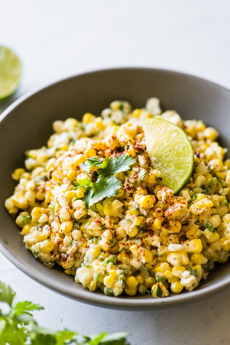 Esquites in a bowl garnished with cilantro leaves.