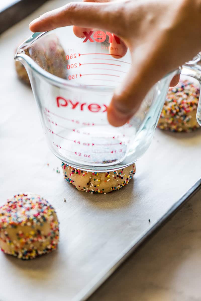 A sprinkle cookie dough ball being flattened