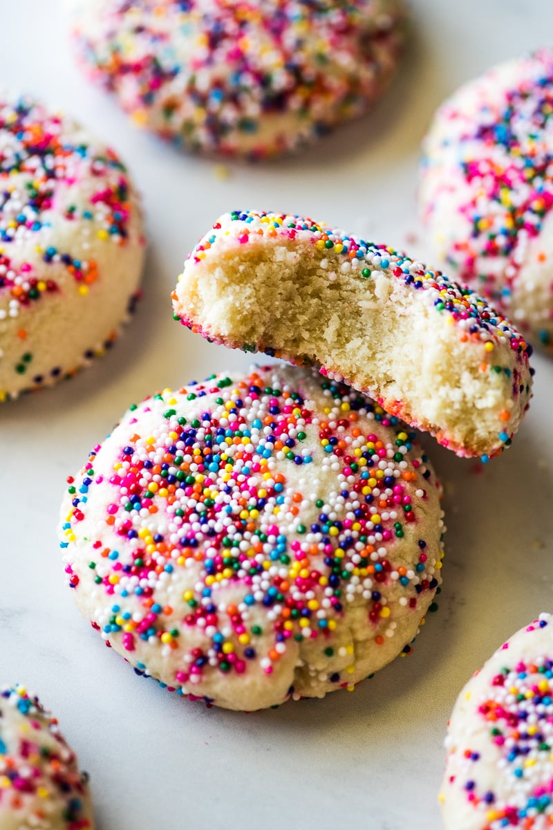 A sprinkle cookie with a bite taken out of it.