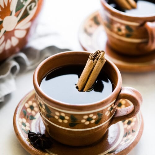 Cafe de olla (traditional Mexican coffee) in a mug with a cinnamon stick.
