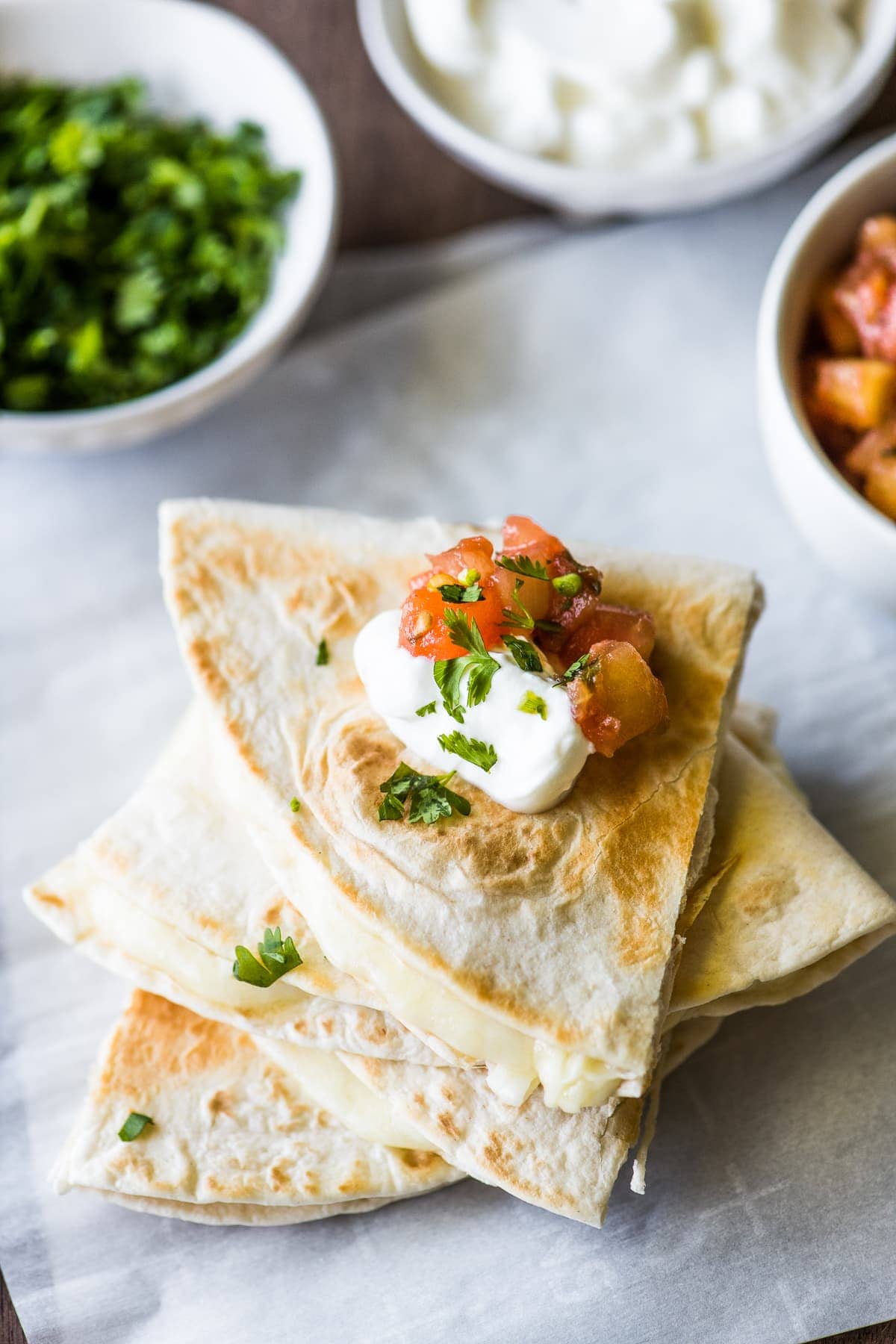 A cheese quesadilla topped with sour cream and pico de gallo.