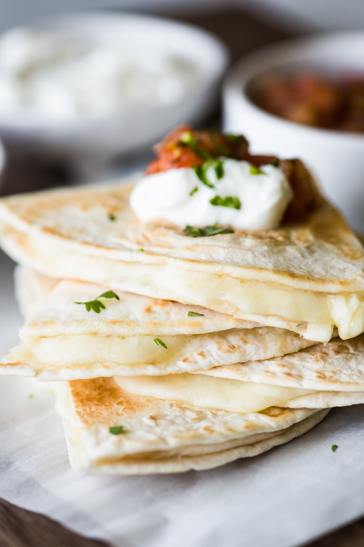 A cheese quesadilla with melted cheese oozing out of the tortilla.