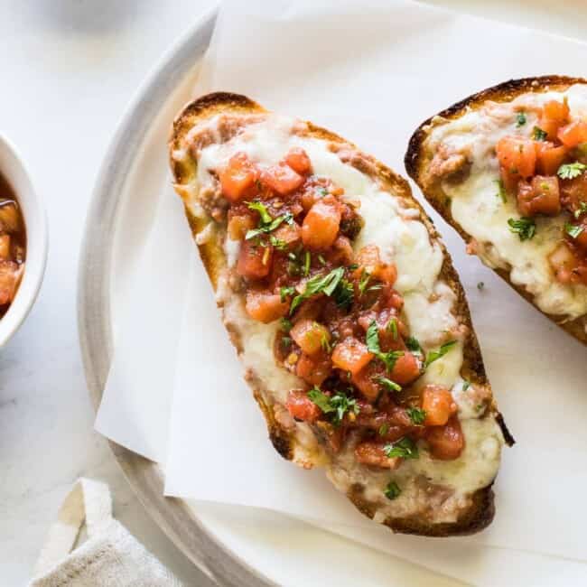 Molletes topped with refried beans, cheese and salsa.