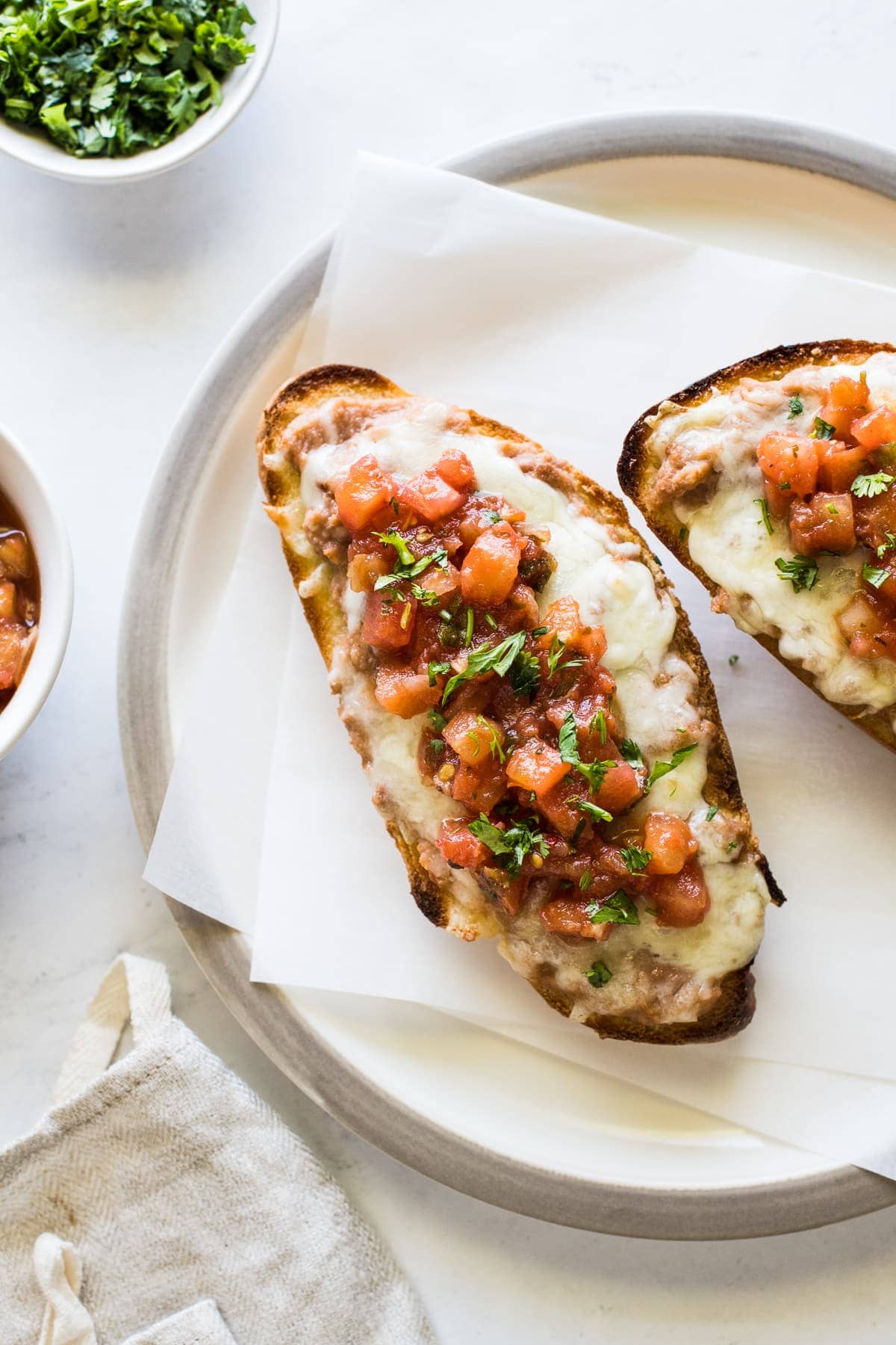 Molletes topped with refried beans, cheese and salsa.