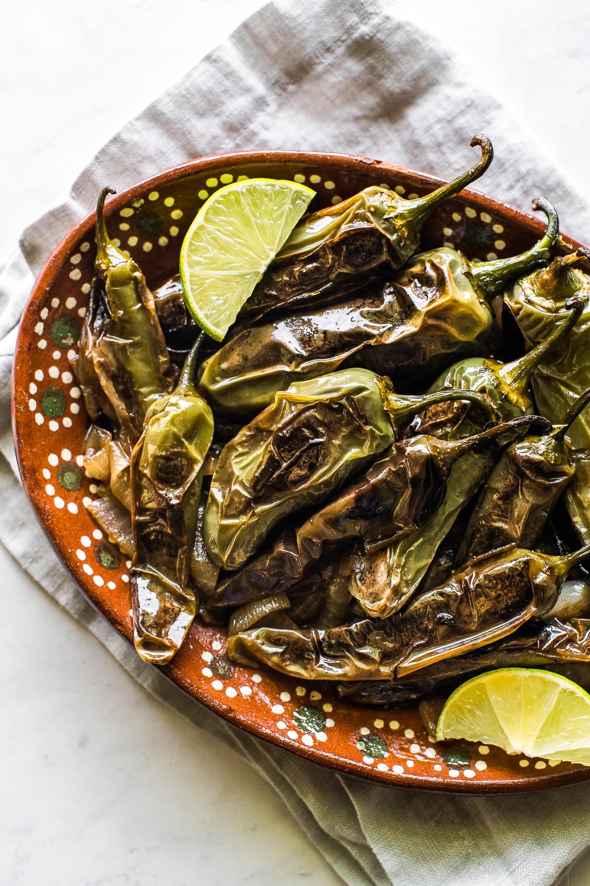 Chiles toreados on a plate with fresh lime wedges.