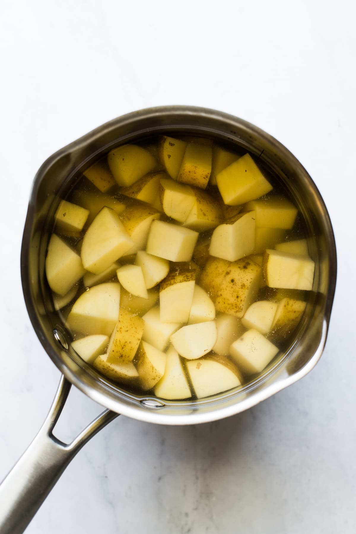 Potatoes cooking in a small saucepan.