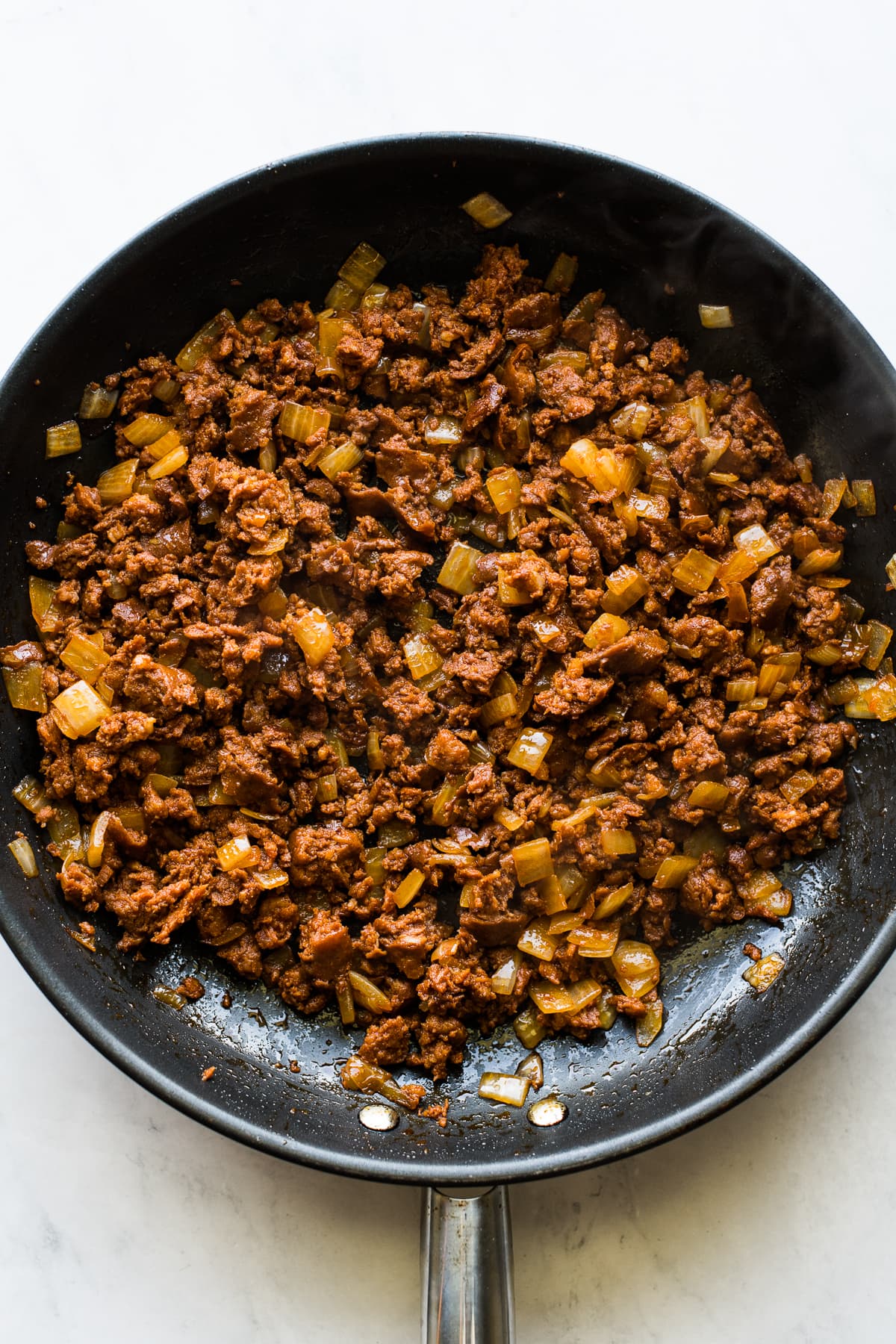 Cooked chorizo and onions in a skillet.