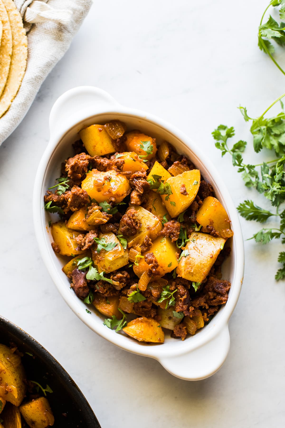 Papas con chorizo in a bowl topped with fresh cilantro.