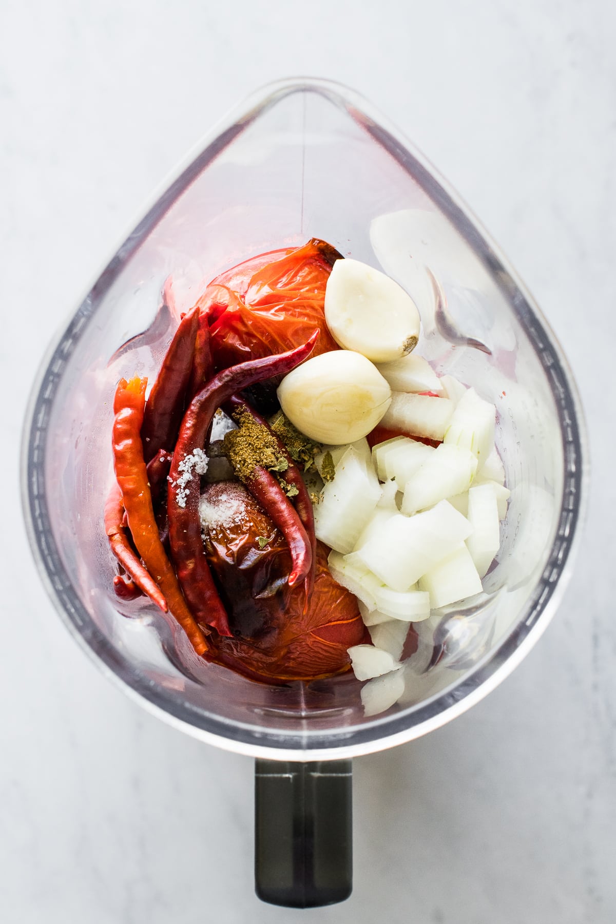 Chile de arbol peppers, onions, tomatoes, garlic and spices in a blender.