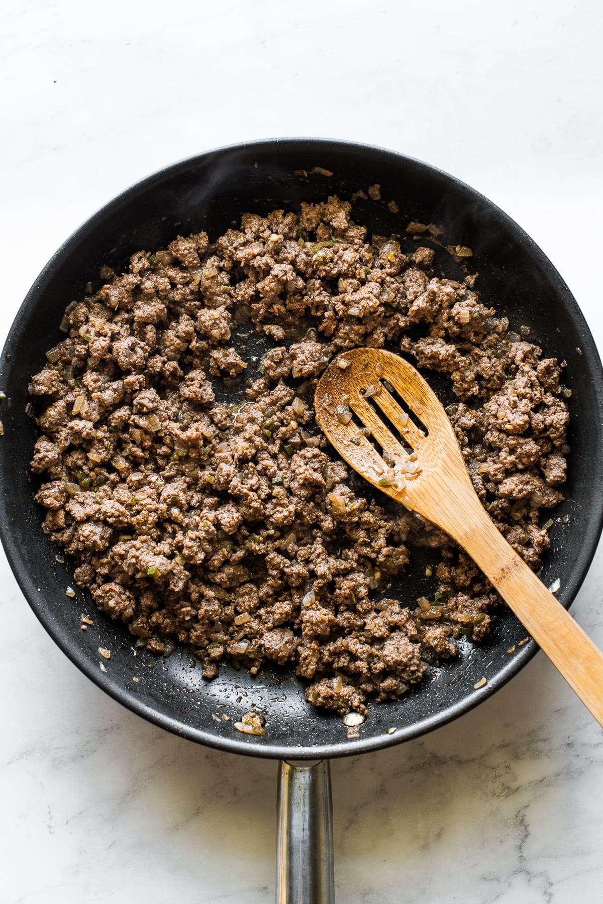 Ground beef sauteed in a large skillet for beef enchiladas.