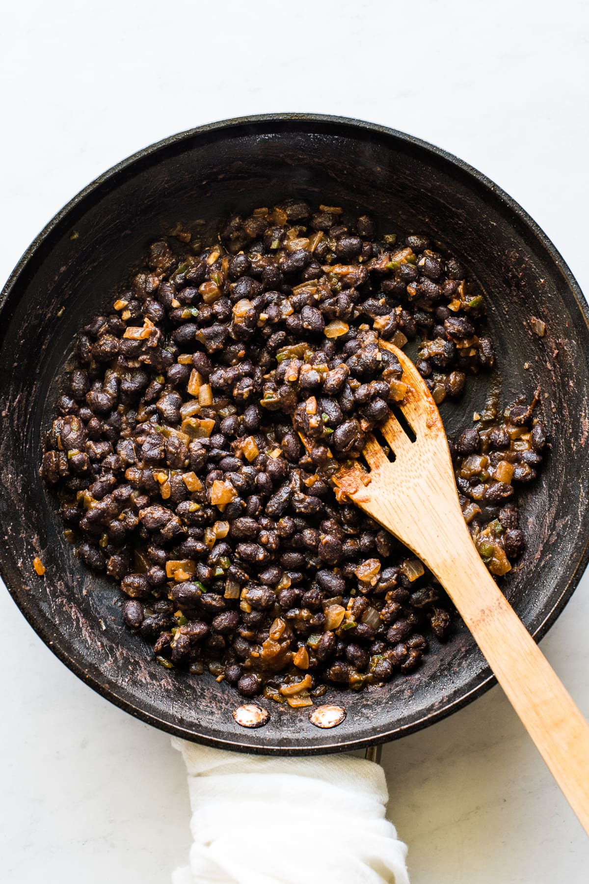 Black beans cooking in a skillet with spices and seasonings.