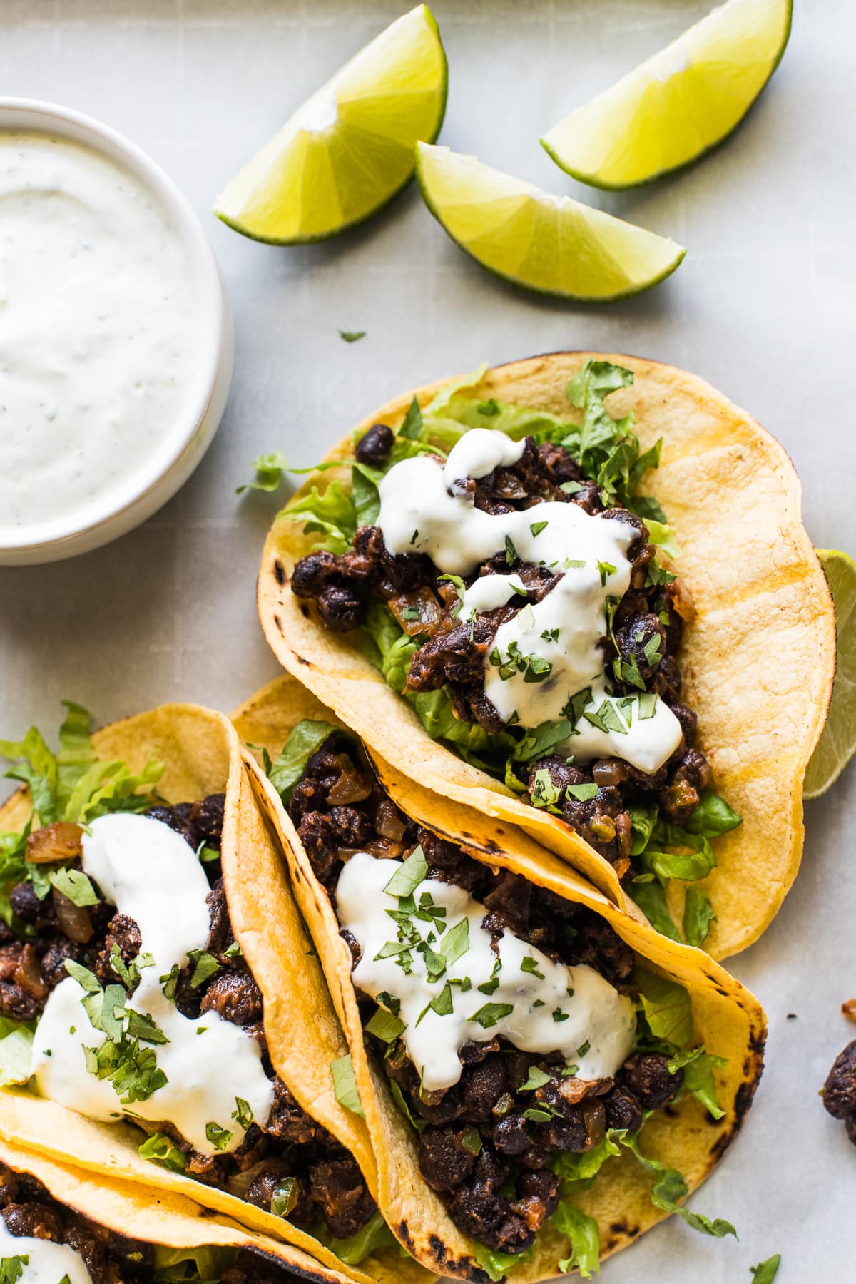 Black bean tacos in a corn tortilla with lime wedges.