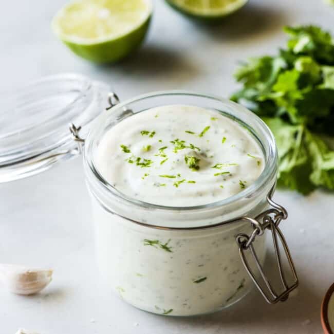 Cilantro lime crema in a jar topped with chopped cilantro.