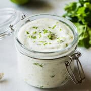 Cilantro lime crema in a jar topped with chopped cilantro.
