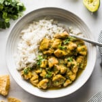 Chicken chile verde in a bowl with white rice topped with cilantro.