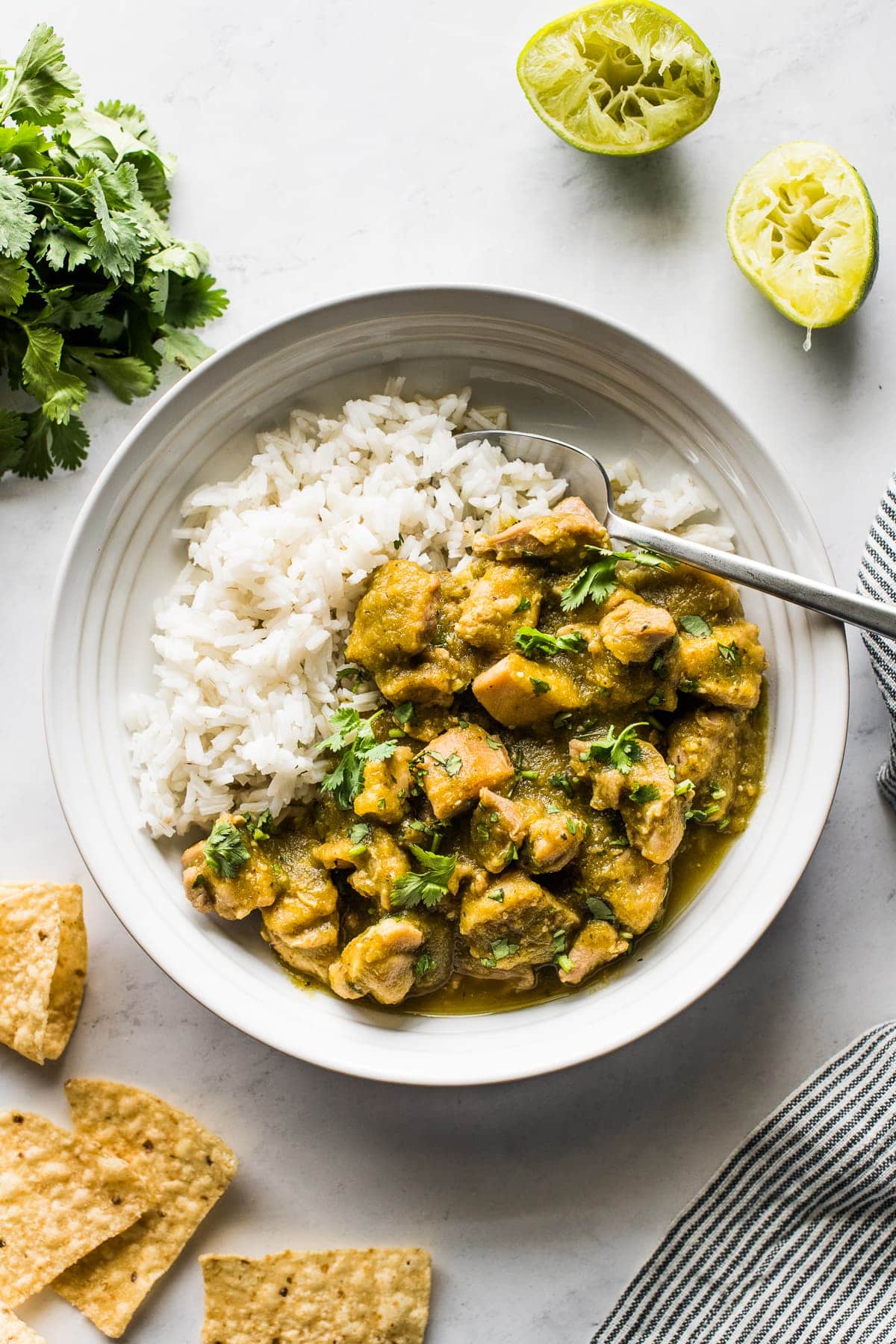 Chicken chile verde in a bowl with white rice topped with cilantro.