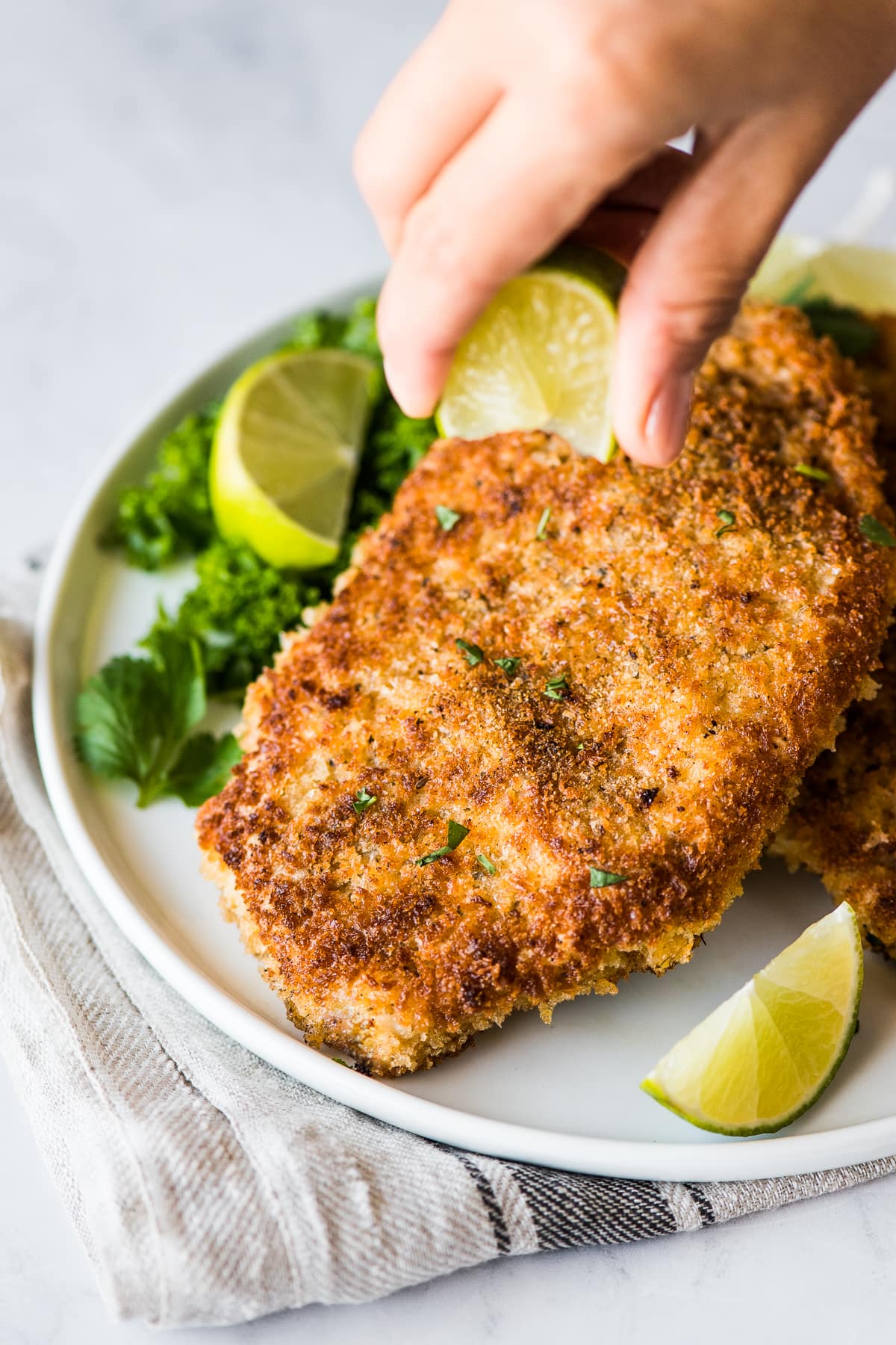 Pork Cutlets on a plate with lime juice being squeezed on top.