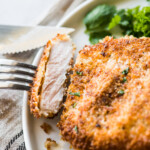 A slice of crispy breaded pork cutlet on a fork ready to eat.