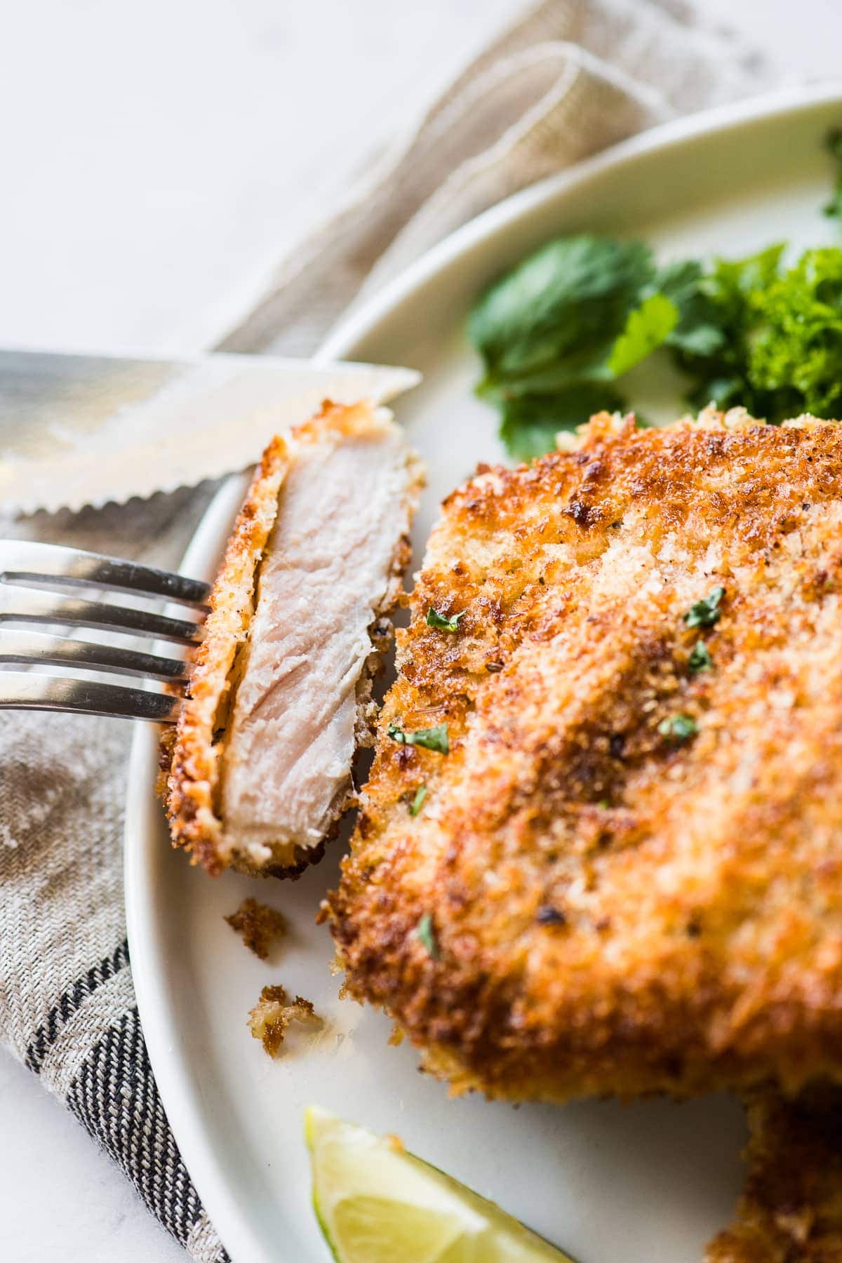 A slice of crispy breaded pork cutlet on a fork ready to eat.