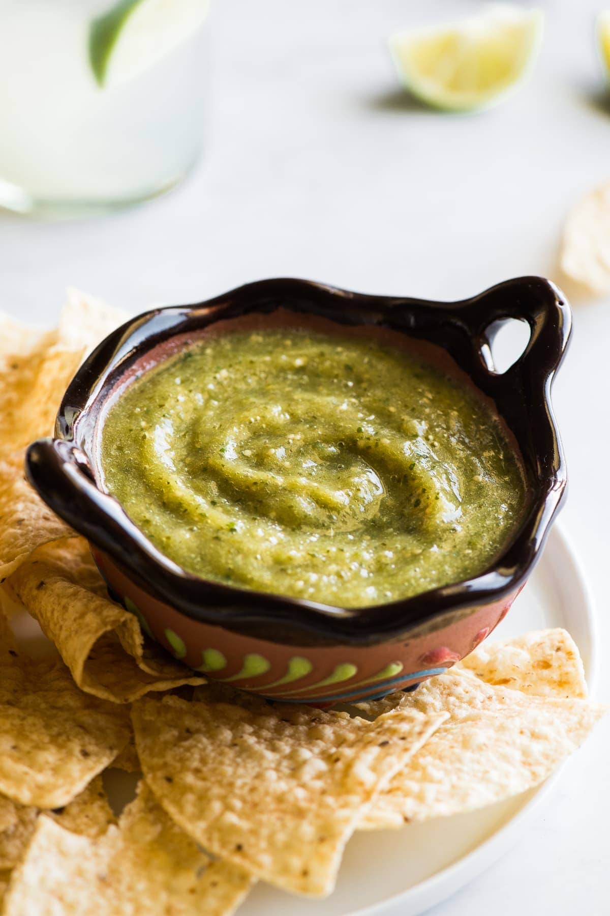 Salsa verde in a Mexican bowl next to some tortilla chips.