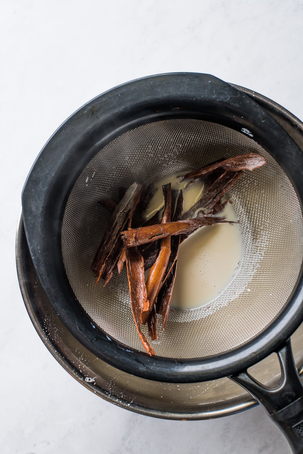 Cinnamon stick pieces in a strainer for making atole.