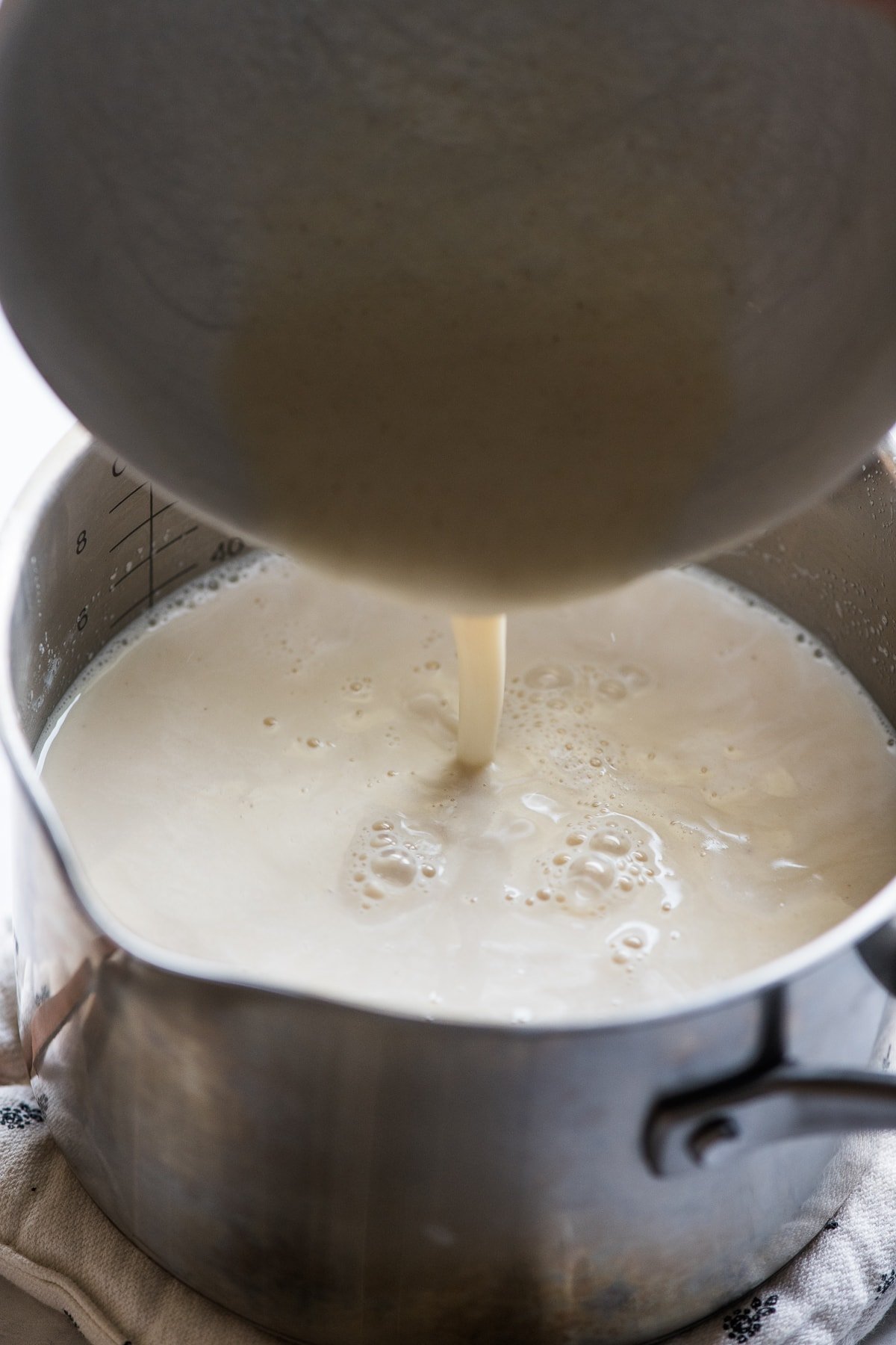 Pouring the masa harina mixture into the milk mixture for atole.