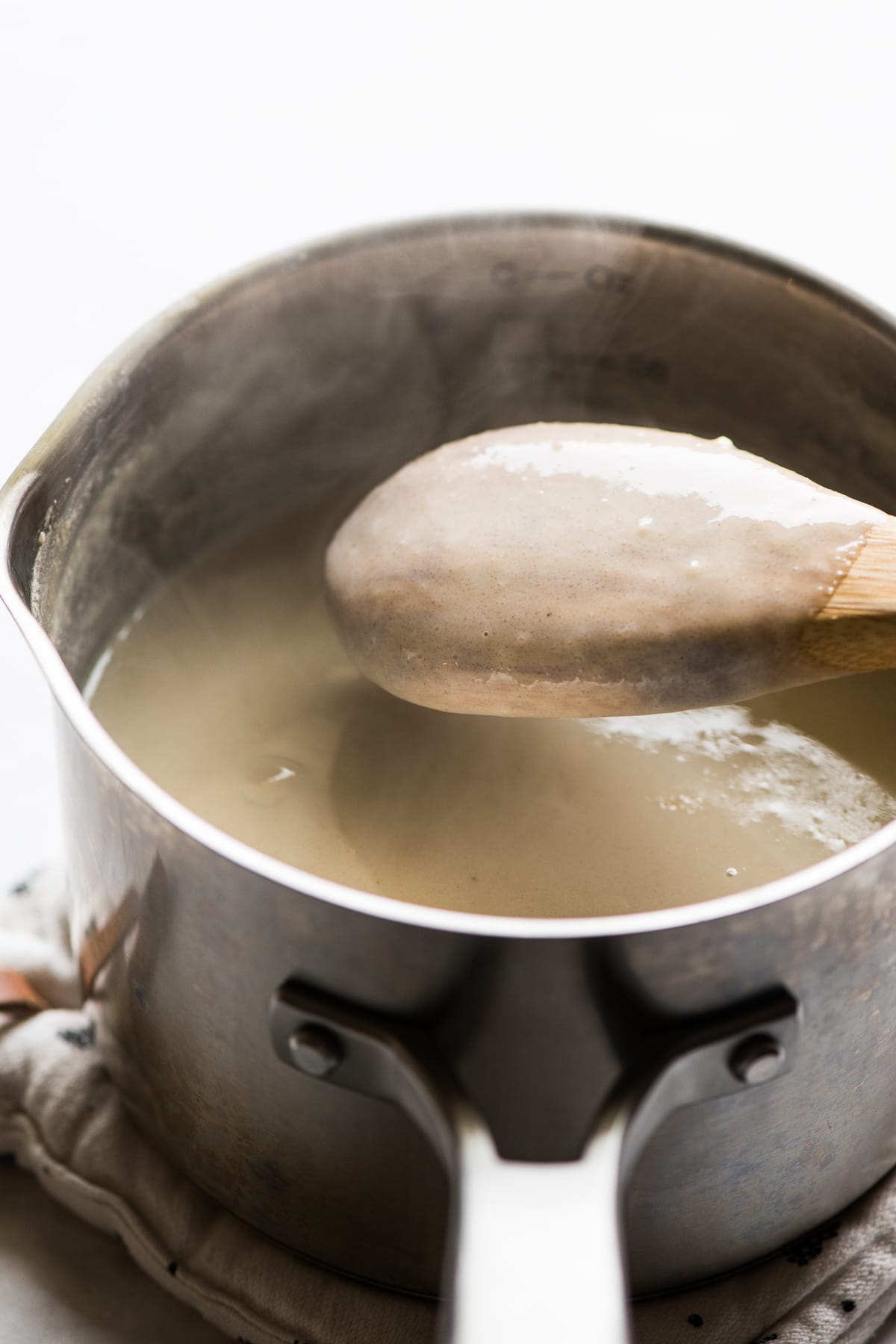 A thickened atole ready to eat coats the back of a wooden spoon.