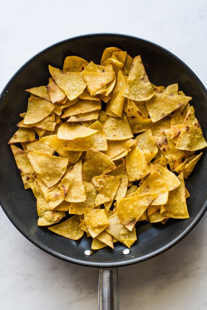 Crispy fried tortilla chips in a large skillet.