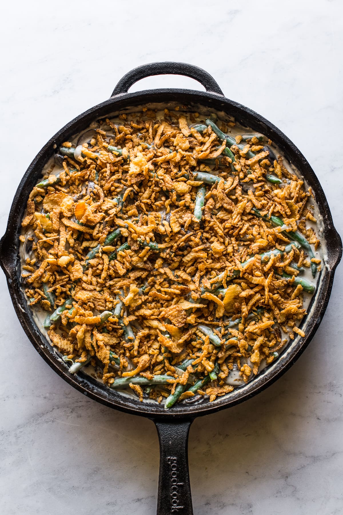 French's fried onions sprinkled on top of green bean casserole, ready to be baked.