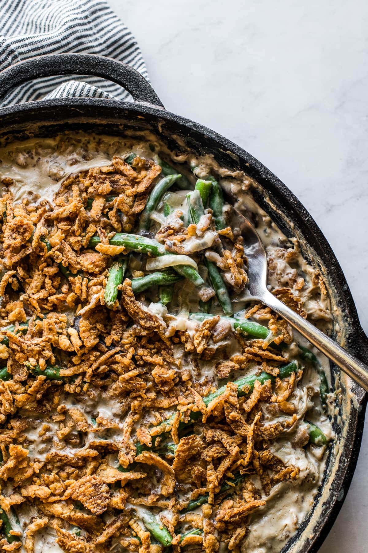 A spoon grabbing a portion of green bean casserole to serve.