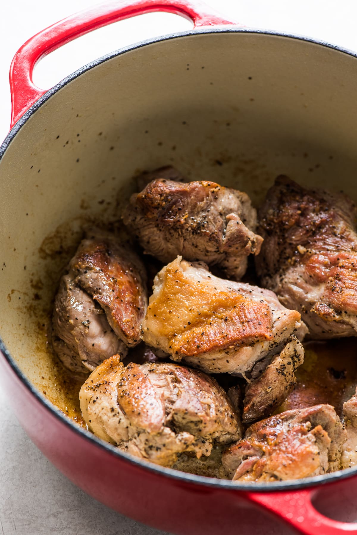 Seared chunks of pork shoulder in a Dutch oven for making pozole.