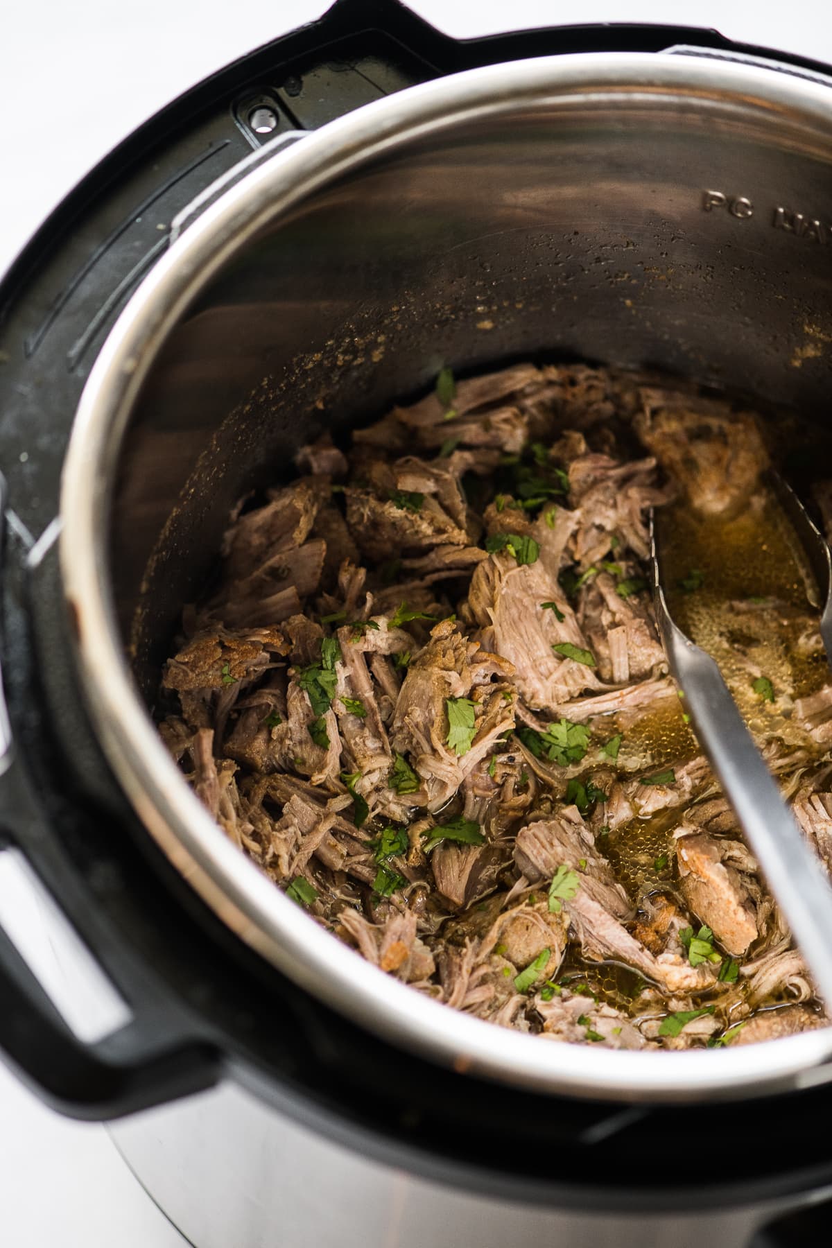 Shredded pork carnitas in an Instant Pot pressure cooker.