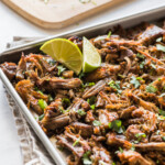 Crispy pressure cooker carnitas topped with cilantro on a baking sheet.