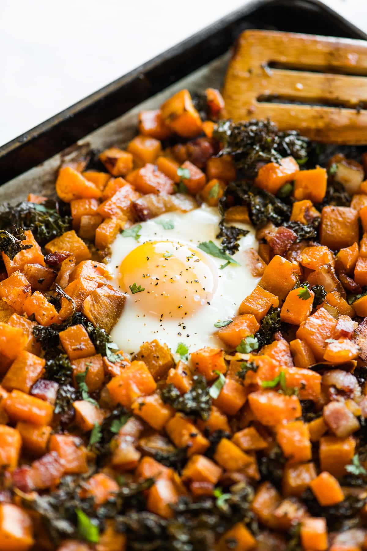 A cooked egg on a sheet pan topped with salt, pepper, and cilantro.