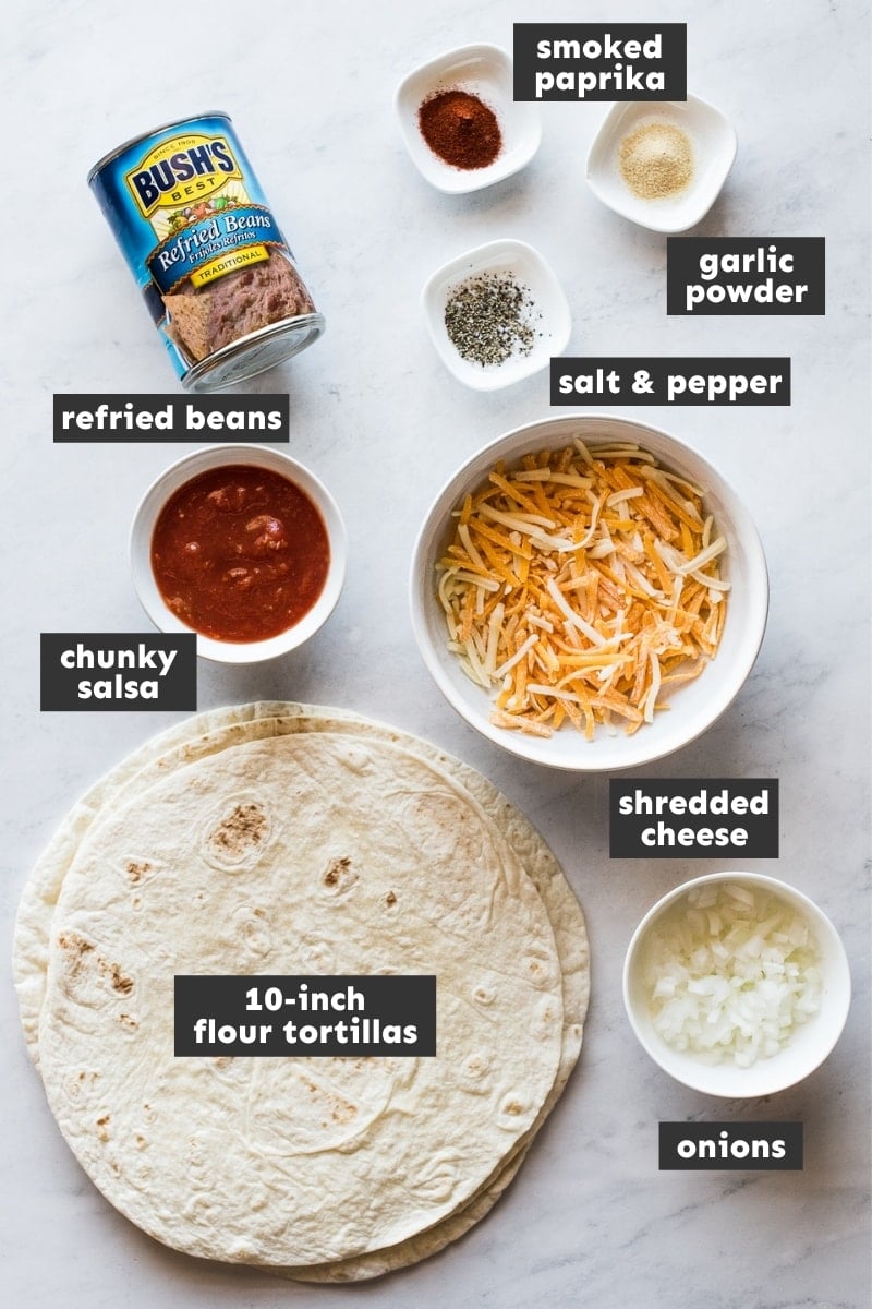 Ingredients in bean and cheese burritos laid out on a table.